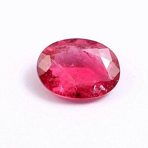 May include: A vibrant pink oval-shaped gemstone with a faceted cut.