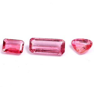 May include: Three pink gemstones, two are rectangular and one is a heart shape.