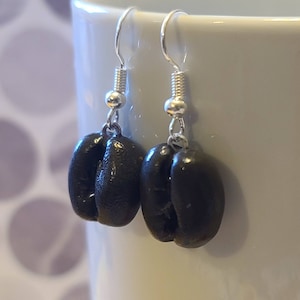 May include: A pair of silver dangle earrings with black coffee bean charms.
