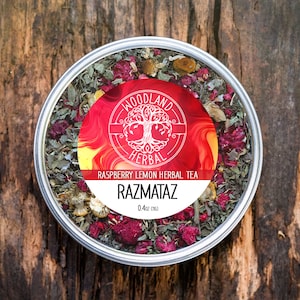 May include: A silver tin of Woodland Herbal Raspberry Lemon Herbal Tea, labeled "Razmataz" with a red, yellow, and orange swirl design. The tin contains loose leaf tea.