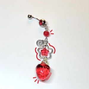 May include: A silver body piercing with a red strawberry charm, a red star charm, and a silver swirl charm. The charm hangs from a silver chain.
