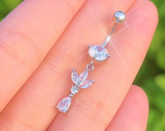 May include: A silver belly button ring with a clear crystal flower charm. The flower has five petals and a small round crystal in the center.