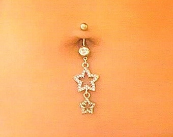 Peut inclure: Gros plan sur un piercing au nombril avec un charme en forme d'étoile dorée qui pend.