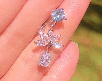 May include: A silver dangle earring with a clear crystal flower and a teardrop-shaped crystal pendant.