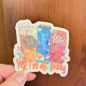 May include: A holographic sticker featuring three beverage containers: a Seven Brew coffee cup, a blue Alani Nu energy drink can, and a red Dr. Pepper can. The sticker includes the text "Yes, I've ate today" and decorative star shapes.