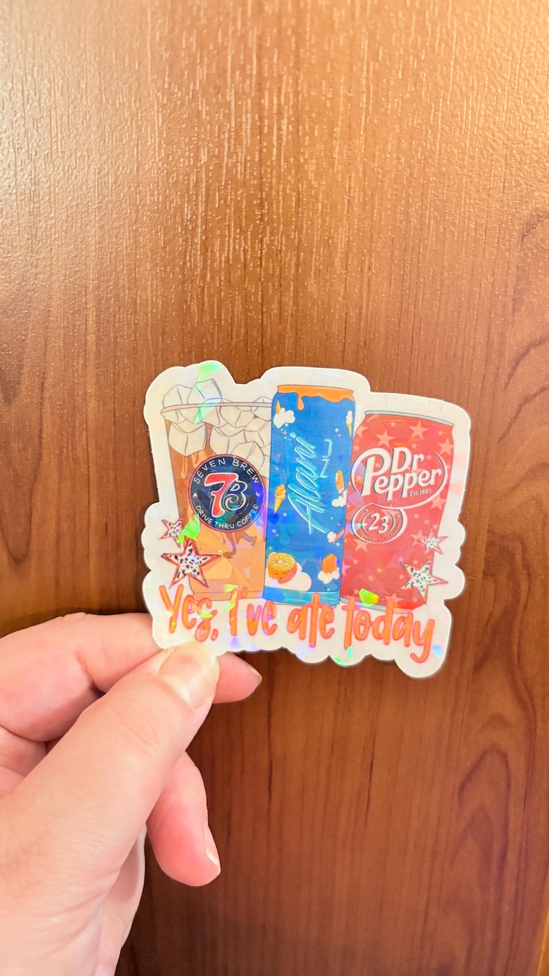 May include: A holographic sticker featuring illustrations of a Seven Brew coffee cup, an Alani Nu energy drink can, and a Dr. Pepper can. The text "Yes, I've ate today" is printed in orange at the bottom, surrounded by small star shapes.