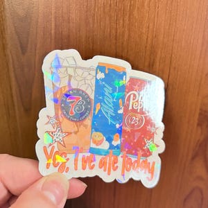 May include: A holographic sticker featuring illustrations of a Seven Brew coffee cup, a blue Alani energy drink can, and a red Dr. Pepper can. The text "Yes, I've ate today" is printed in orange at the bottom, accented by small star shapes.