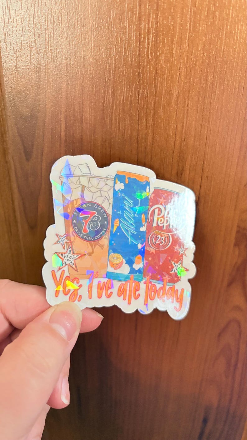 May include: A holographic sticker featuring illustrations of a Seven Brew coffee cup, a blue Alani energy drink can, and a red Dr. Pepper can. The text "Yes, I've ate today" is printed in orange at the bottom, accented by small star shapes.