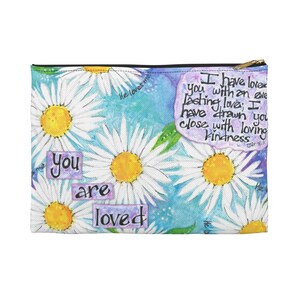 May include: A white zippered pouch with a floral pattern of white daisies with yellow centers on a blue background. The text "You are loved" is printed in purple and yellow on the bottom left corner. The text "I have loved you with an everlasting love; I have drawn you close with loving kindness" is printed in black on a purple background in the upper right corner.