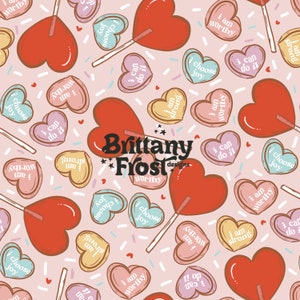 May include: A pink background with a repeating pattern of red heart-shaped lollipops and candy hearts. The candy hearts have various positive messages on them, such as "I am worthy", "I choose joy", and "I can do it". The text "Brittany Frost Designs" is in the center of the image.
