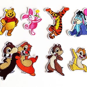 Könnte beinhalten: Satz von zehn gestickten Bügelbildern mit verschiedenen Disney-Charakteren, darunter Winnie Puuh, Tigger, Ferkel und Chip und Chap.