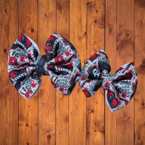 May include: Three fabric hair bows with a horror movie theme. The bows feature a white background with red accents, images of a ghost face, and the text "Billy" and "Do you like scary movies?"