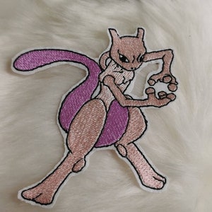 Könnte beinhalten: Ein gestickter Bügel-Patch mit einem pinkfarbenen und violetten Pokémon-Charakter, bekannt als "Mewtwo", in Kampfpose.