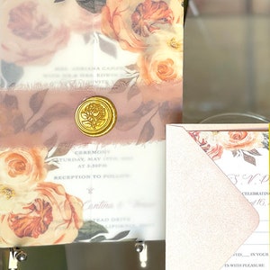 Puede incluir: Elegante juego de invitaciones de boda con dise&ntilde;os florales en tonos melocot&oacute;n y crema. La invitaci&oacute;n incluye un sello de cera dorado y una cinta rosa suave. El texto de la invitaci&oacute;n dice "Mrs. Adriana Camp...Invite".