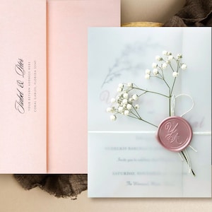 Puede incluir: Un conjunto de invitaciones de boda rosa rubor con una superposici&oacute;n de vitela, flores blancas y un sello de cera rosa. La invitaci&oacute;n incluye los nombres "Ysabel & Peter" y la direcci&oacute;n de devoluci&oacute;n.
