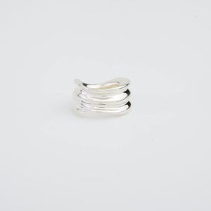 Può includere: Un anello d'argento con un design ondulato e organico. L'anello è composto da più strati di metallo impilati uno sopra l'altro.