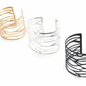 Three cuff bracelets 'Branching' with unique designs: polished silver, black-plated silver, and brass, featuring a branch-inspired motif.