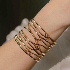 A woman wears a brass Bracelet 'Branching' with detailed natural motifs, a stylish gift idea for women who love organic and sculptural jewelry.