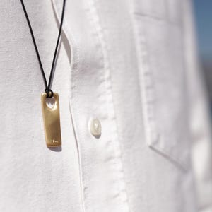 A man in a white shirt wears a matte gold plated silver bar necklace for men, showcasing a minimalist and sophisticated style.