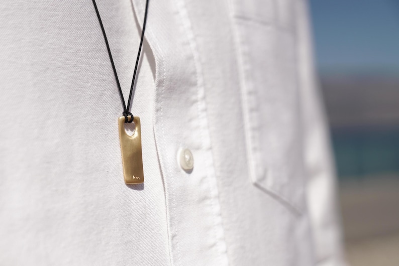 A man in a white shirt wears a matte gold plated silver bar necklace for men, showcasing a minimalist and sophisticated style.