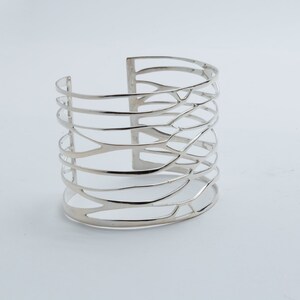 Bold and elegant silver cuff bracelet with a wide design, handcrafted for a unique, high-fashion jewelry look.