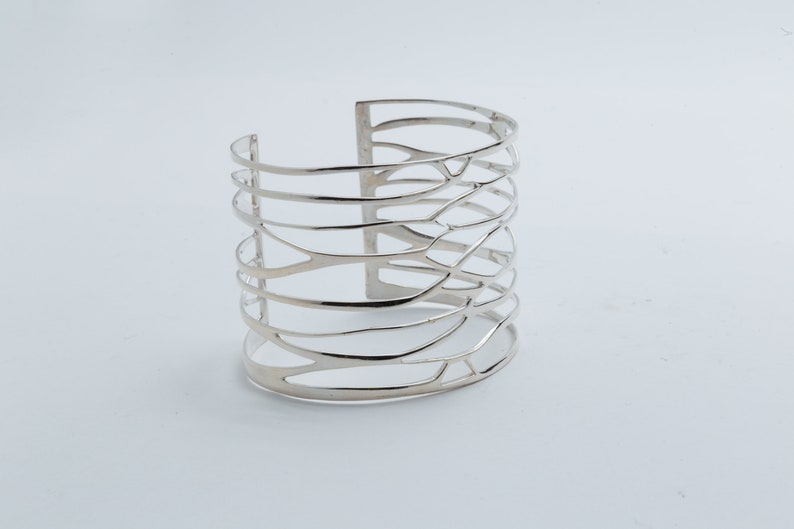 Bold and elegant silver cuff bracelet with a wide design, handcrafted for a unique, high-fashion jewelry look.
