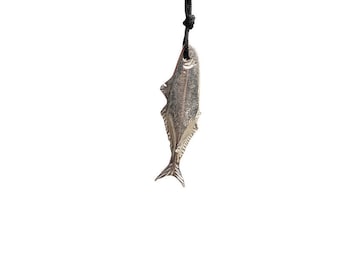 Könnte beinhalten: Ein silberner Fisch-Anhänger, der an einer schwarzen Schnur hängt. Der Anhänger ist mit Schuppen und Flossen verziert.