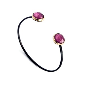 May include: A black bangle bracelet with two pink gemstone accents.