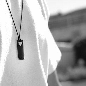 A man in a white t-shirt wearing a black plated silver men's bar necklace , showcasing a stylish minimalist look.