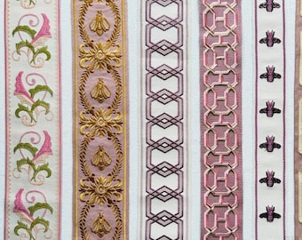 May include: Seven vertical strips of decorative fabric trim featuring various embroidered patterns. Designs include pink and green floral motifs, gold bees in laurel wreaths, geometric lattice, pink chain links, small purple bees, gold scrollwork, and white loops.
