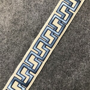 May include: Beige trim with a blue geometric pattern. The trim has a raised, embroidered design.