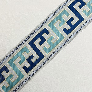 Pode incluir: Trimming azul e branco com um padr&atilde;o geom&eacute;trico. O trimming apresenta um desenho repetitivo de quadrados com um motivo de chave grega.