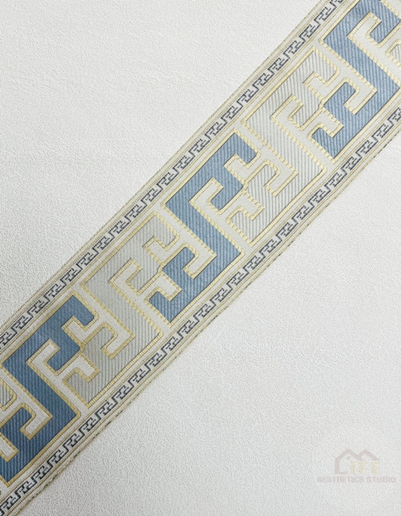 Pode incluir: Uma guarni&ccedil;&atilde;o branca e azul com um design geom&eacute;trico. A guarni&ccedil;&atilde;o apresenta um padr&atilde;o repetido de um motivo de chave grega.