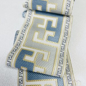 Pode incluir: Acabamento de tecido com padr&atilde;o azul e dourado com um design geom&eacute;trico. O acabamento &eacute; tecido com um tecido texturizado e tem um fundo branco.