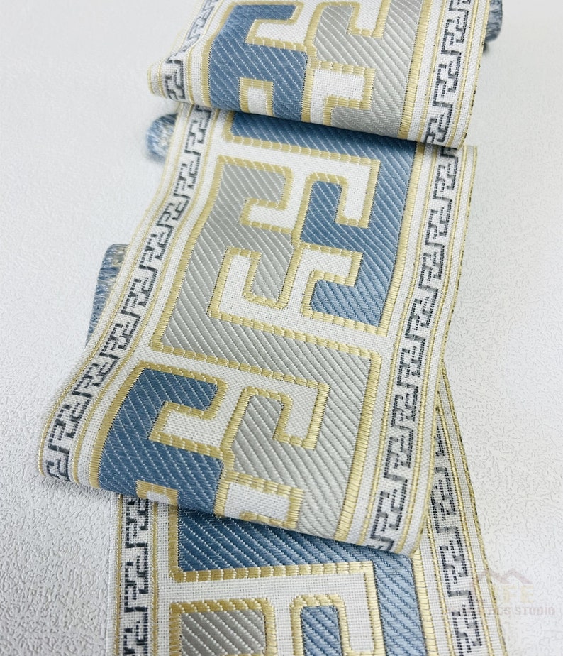 Pode incluir: Acabamento de tecido com padr&atilde;o azul e dourado com um design geom&eacute;trico. O acabamento &eacute; tecido com um tecido texturizado e tem um fundo branco.