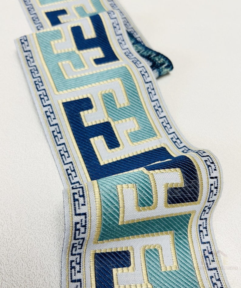 Pode incluir: Trimming azul e verde com um design de chave grega dourada. O trimming &eacute; tecido e tem um fundo branco.