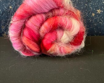 May include: A ball of pink, white, and red wool yarn. The yarn is arranged in a spiral shape.