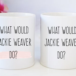 Puede incluir: Dos tazas de cerámica blanca con texto negro que dice "What would Jackie Weaver do?" Una taza tiene una franja rosa en la parte inferior.