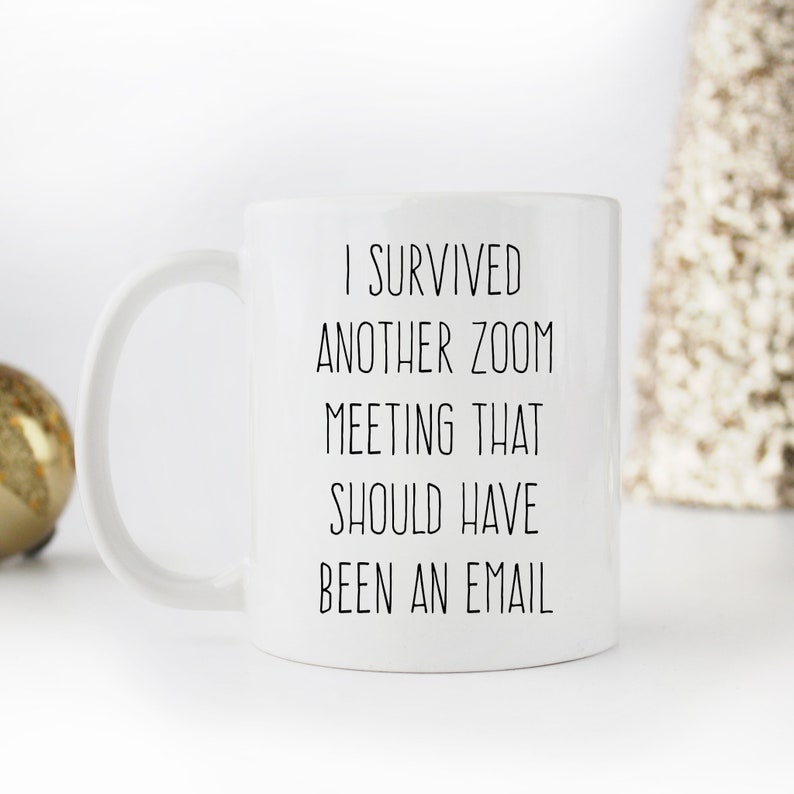 Pu&ograve; includere: Una tazza da caff&egrave; in ceramica bianca con testo nero che recita "Sono sopravvissuto a un'altra riunione Zoom che avrebbe dovuto essere un'e-mail."