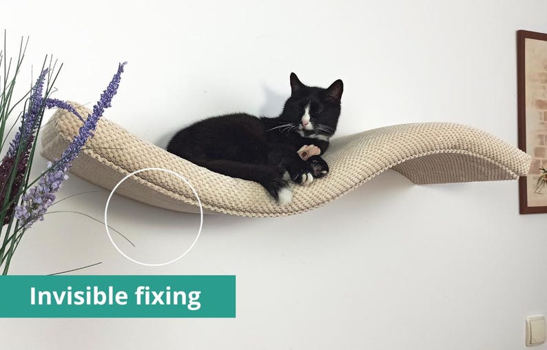 May include: A wall-mounted cat shelf with a curved, wave-like design and a textured, beige fabric surface. A black and white cat is resting on the shelf. The product features an invisible fixing system as indicated by the text on the image.