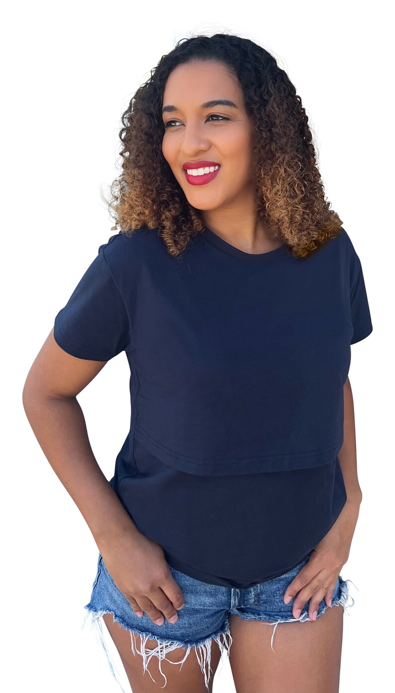 May include: A solid navy blue short-sleeved t-shirt featuring a horizontal overlay panel across the chest, paired with blue denim shorts that have a frayed, raw-edge hemline. The t-shirt has a classic crew neckline and a simple, clean design.