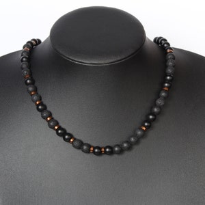 May include: A black beaded necklace with copper accents. The necklace is made of black lava rock and black onyx beads.