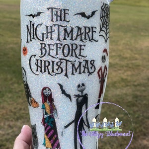 May include: White glitter tumbler with a black and white image of characters from the movie "The Nightmare Before Christmas". The text "The Nightmare Before Christmas" is printed on the tumbler.