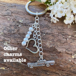 May include: Silver charm keychain with a car, heart, and pearl beads. Other charms available.
