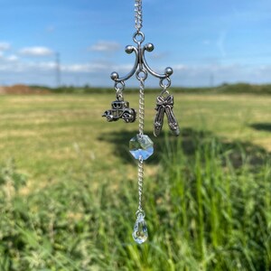 Peut inclure: Un charme de voiture argenté et une paire de chaussures argentées en charme pendent à une chaîne argentée avec des perles de cristal et une larme de cristal. Le charme est suspendu à un support argenté de style lustre.