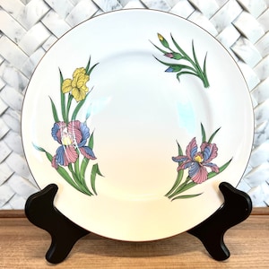 May include: White ceramic dinner plate with a gold rim and a floral design featuring yellow, pink, blue, and green irises.