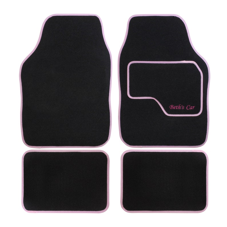May include: Set of four black car floor mats with pink edging. The driver's side mat has a pink rectangle with the text "Beth's Car" embroidered in pink.