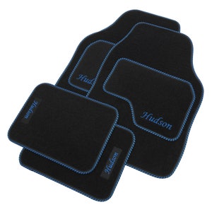 May include: Set of four black car floor mats with blue edging and the name "Hudson" embroidered in blue on each mat.