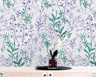Op de afbeelding: Een licht houten kast met glazen deuren en planken tegen een witte muur met een paars en groen bloemenpatroon behang.