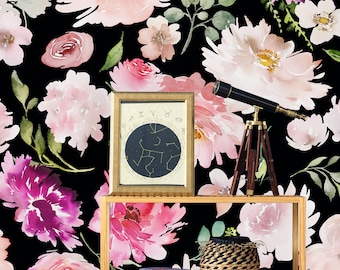 May include: A wooden shelf with a black and gold framed picture of a constellation chart, a telescope on a tripod, and a woven basket. The shelf is in front of a black background with a watercolor floral pattern in pink, white, and purple.